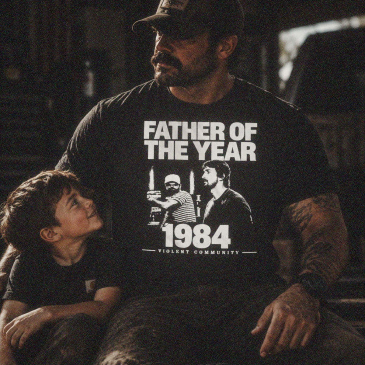 Father wearing Father of the Year 1984 Violent Community shirt with his son
