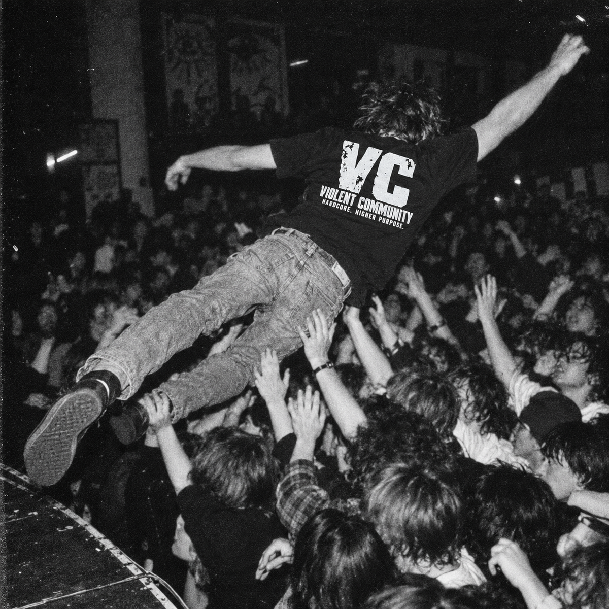 AI-generated punk concert mockup showing the Hardcore Higher Purpose back print on a crowd-jumping attendee